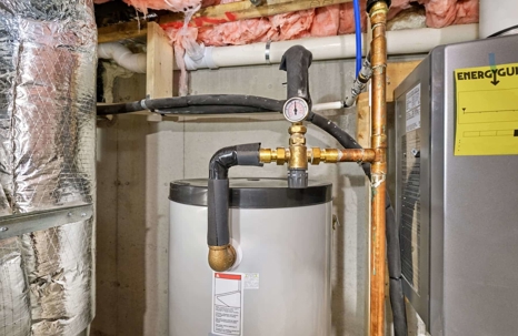 A residential hot water heater with associated plumbing and a visible ENERGYGUIDE sticker